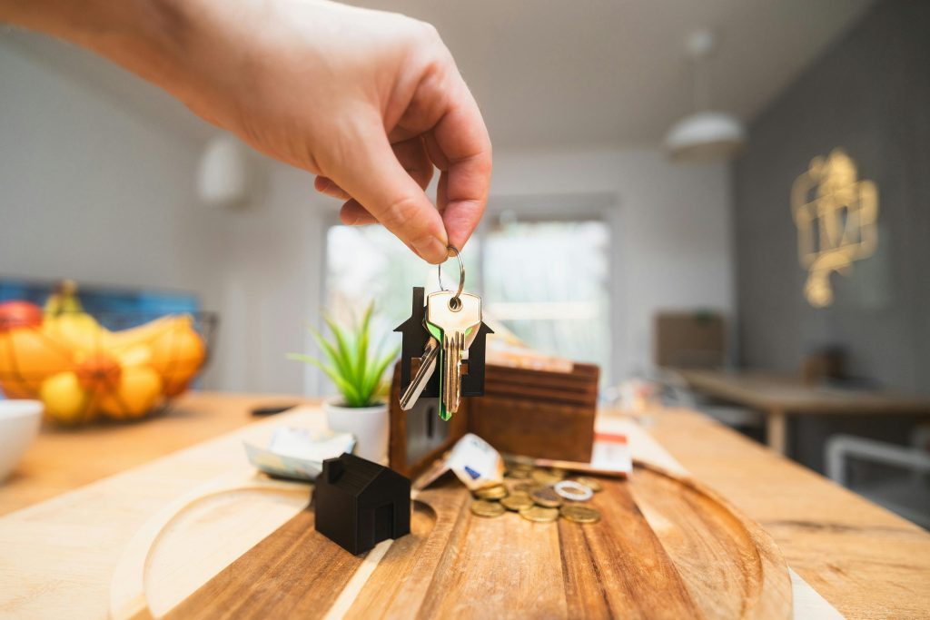 hand holding a set of keys on a house keychain over a wooden desk